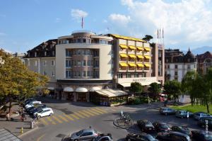 a large building with cars parked in a parking lot at Astra Vevey Hotel & Restaurant in Vevey