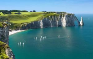 a boat in a body of water next to a cliff at Prestige Étretat in Étretat
