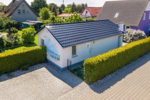 a small white house with a blue roof in a yard at FH Mimi in Ostseebad Karlshagen