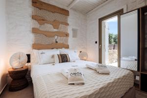 a bedroom with a large white bed with towels on it at Onos Luxury Villas Kythnos in Kithnos +35 photos
