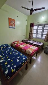 a bedroom with two beds and a ceiling fan at Malgudi Mane Homestay in Chikmagalūr