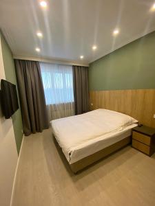 a bedroom with a large bed and a window at Komrat Apartments in Almaty