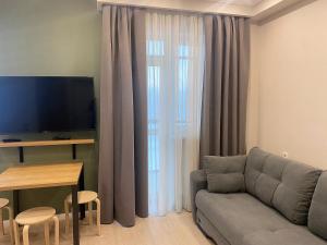 a living room with a couch and a table and a television at Komrat Apartments in Almaty