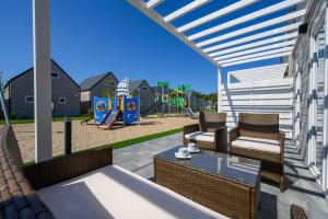 a patio with a table and chairs and a playground at RESORT za lasem II in Jarosławiec