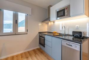 a kitchen with a sink and a microwave at Casas das Hortas, Apartamento Vista Mar in Seixal