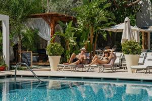 two women sitting in chairs next to a swimming pool at Ölüdeniz Blu Luxury Unique Hotel - Adults-Only in Oludeniz +37 photos
