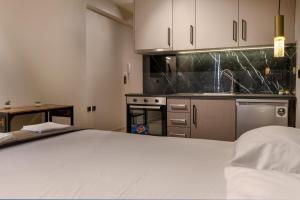a kitchen with white cabinets and a bed in a room at Dimitra's studio in Preveza +2 photos