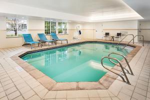 Una piscina en una habitación de hotel con sillas y mesas. en TownePlace Suites by Marriott Colorado Springs South, en Colorado Springs