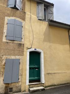 a building with a green door and two windows at Alembert - En plein centre ville - 1er étage in Auch +1 photo