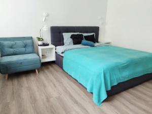 a bedroom with a blue bed and a chair at Modern Courtyard Condo in Liepāja