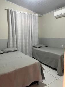 a bedroom with two beds and a window with curtains at Canto da Gaivota Lençóis Maranhenses in Santo Amaro
