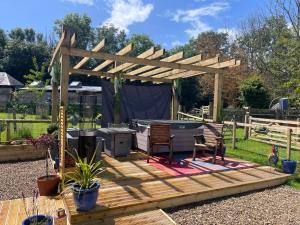 a wooden deck with a pergola in a garden at Millburn Mini Farm in Kilwinning