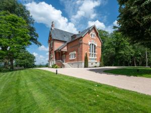 un grande edificio in mattoni rossi con un prato di Cottage de Montchamp a Châtenay