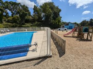 a fence around a swimming pool with a playground at Grand Mobilhome 4 pers 2025 - Granit Rose - Piscine in Kermaria-Sulard
