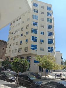 a large white building with cars parked in a parking lot at Home Darna City Center in Tangier