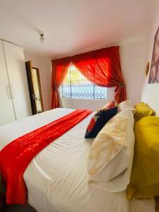 a bedroom with a large bed with a red curtain at The Fern Corner Guest House in Nkowakowa