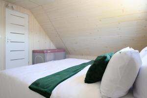 a bedroom with a bed with green and white pillows at RESORT za lasem II in Jarosławiec +19 photos