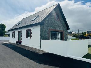 a small white house with a black roof at De Búrca Cottage KERRY in Brackhill