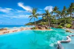 茶云莱海滩Sheraton Samui Resort的棕榈树和海洋度假村的游泳池