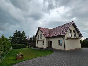 a white house with a red roof and a yard at Sielska Chatka in Sarbinowo