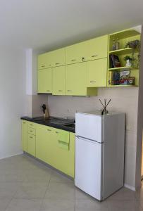 a kitchen with yellow cabinets and a white refrigerator at JOY Studio in Ravda