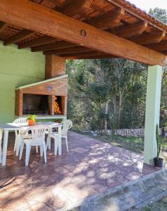 eine Terrasse mit einem Tisch, Stühlen und einem Kamin in der Unterkunft Casa de campo in Los Hornillos