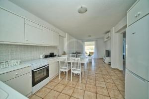 a kitchen with white cabinets and a table and chairs at Armonia Apartment in Ermioni +35 photos