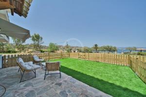 a backyard with a lawn and chairs and a fence at Armonia Apartment in Ermioni