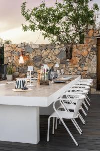 a white table with white chairs and a stone wall at Casa Kalu in São Brás de Alportel