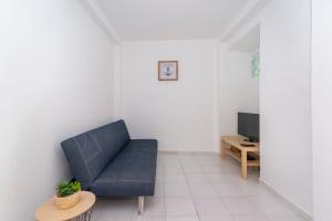 a living room with a blue couch and a tv at Casa Garde - 5 mins city center - private balcony - wi-fi in Tavira