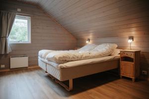 Cama grande en habitación de madera con ventana en Fanøy Island Lodge, en Fanoyna