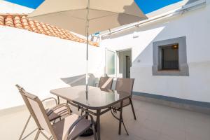 a table and chairs with an umbrella on a patio at Casa Garde - 5 mins city center - private balcony - wi-fi in Tavira