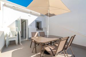 a table and chairs with an umbrella on a balcony at Casa Garde - 5 mins city center - private balcony - wi-fi in Tavira