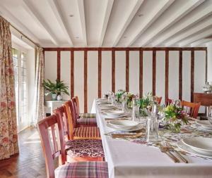 a dining room with a long table with chairs and plates at Cotswold Country house Villa Retreat With Pool in Rowde
