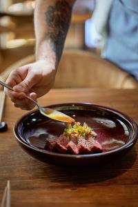 a person holding a fork and a plate of food at Les Suites at The Cliff Bay - PortoBay in Funchal