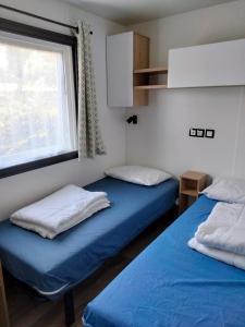 two beds in a small room with a window at Mobil Home Les Charmettes 321 in Les Mathes