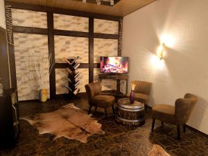 a living room with chairs and a flat screen tv at HAUS BENICO -Pension- in Ernst