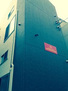 un edificio azul con un cartel en el costado en Shitamachi Base en Tokio