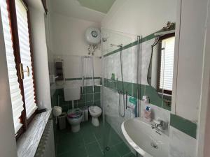 a green and white bathroom with a sink and a toilet at Casa Giulia in Porto SantʼElpidio