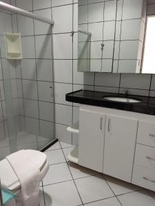 a white bathroom with a sink and a mirror at Apart Hotel Marinas Tamandaré in Tamandaré