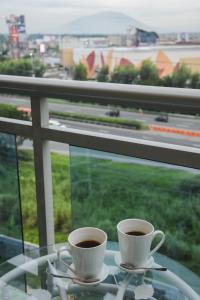 Dos tazas de café en una mesa de cristal frente a una ventana. en Le Monaco Suites - Azure North Pampanga, en San Agustin
