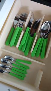a drawer full of utensils with green knives and forks at Apart Hotel Marinas Tamandaré in Tamandaré