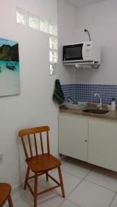 a kitchen with a wooden chair and a microwave at Apart Hotel Marinas Tamandaré in Tamandaré