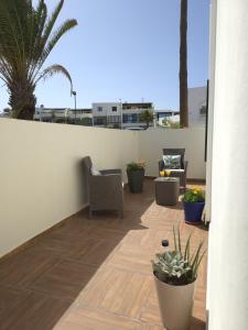 a patio with chairs and potted plants on a balcony at Bungalow Aqua Sol - Playa Roca residence - Sea front access - Free AC - WiFi in Costa Teguise