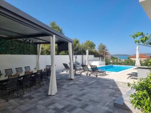 un patio con sillas, un dosel y una piscina en Villa Amaris, en Brodarica