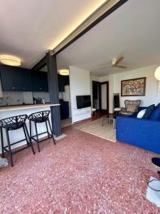 a living room with a blue couch and a kitchen at Elegante apartamento con piscina en el Saler in Valencia