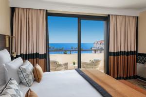 a bedroom with a large bed and a balcony at Hôtel Barrière Le Gray d'Albion in Cannes