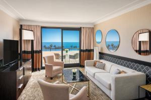 a living room with a couch and chairs and a television at Hôtel Barrière Le Gray d'Albion in Cannes
