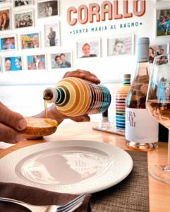a person pouring a drink into a piece of bread at Hotel Corallo in Santa Maria al Bagno