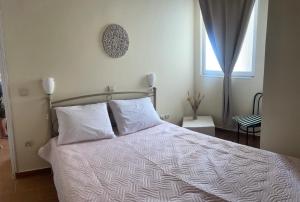 a bed with white sheets and pillows in a bedroom at Elsa Apartment in Aegina Town